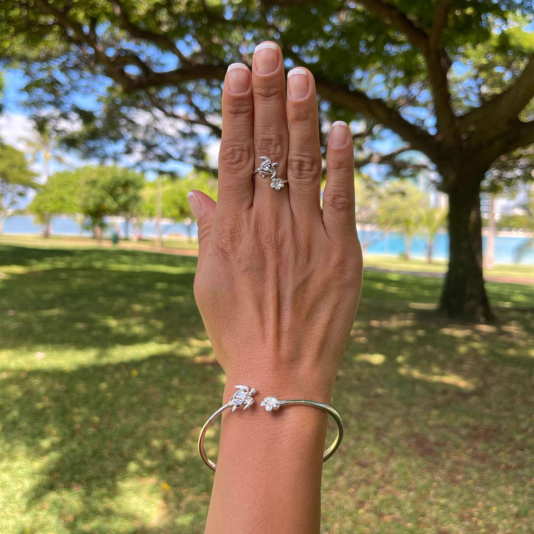 a woman's hand holding a Honu and Plumeria Ring in Sterling Silver from Maui Divers Jewelry.