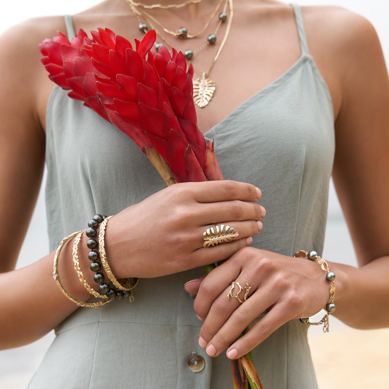 A woman wearing a Plumeria Ring in Two Tone Gold with Diamonds and other jewelry - Maui Divers Jewelry