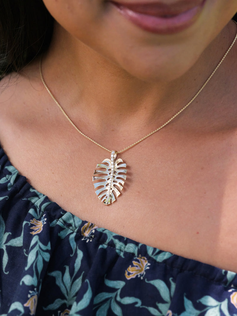 A woman's chest with a Monstera Pendant in Gold with Diamonds - 30mm - Maui Divers Jewelry