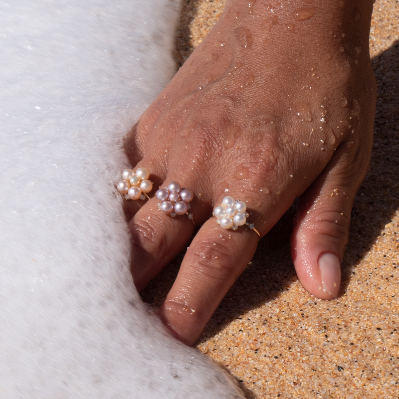A woman's hand in the sand wearing a Tiny Bubbles Lavender Freshwater Pearl Ring in Gold with Diamonds - Maui Divers Jewelry